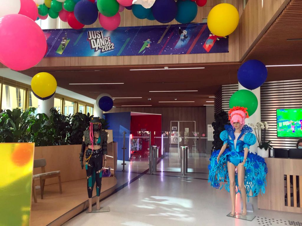 Nuages en ballons colorés, avec des ballons différentes tailles pour le jeu Ubisoft just dance. installation a des hauteurs différentes. Présences de personnages factices dans un hall d'entreprise