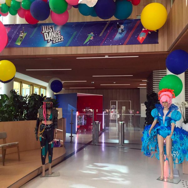Nuages en ballons colorés, avec des ballons différentes tailles pour le jeu Ubisoft just dance. installation a des hauteurs différentes. Présences de personnages factices dans un hall d'entreprise