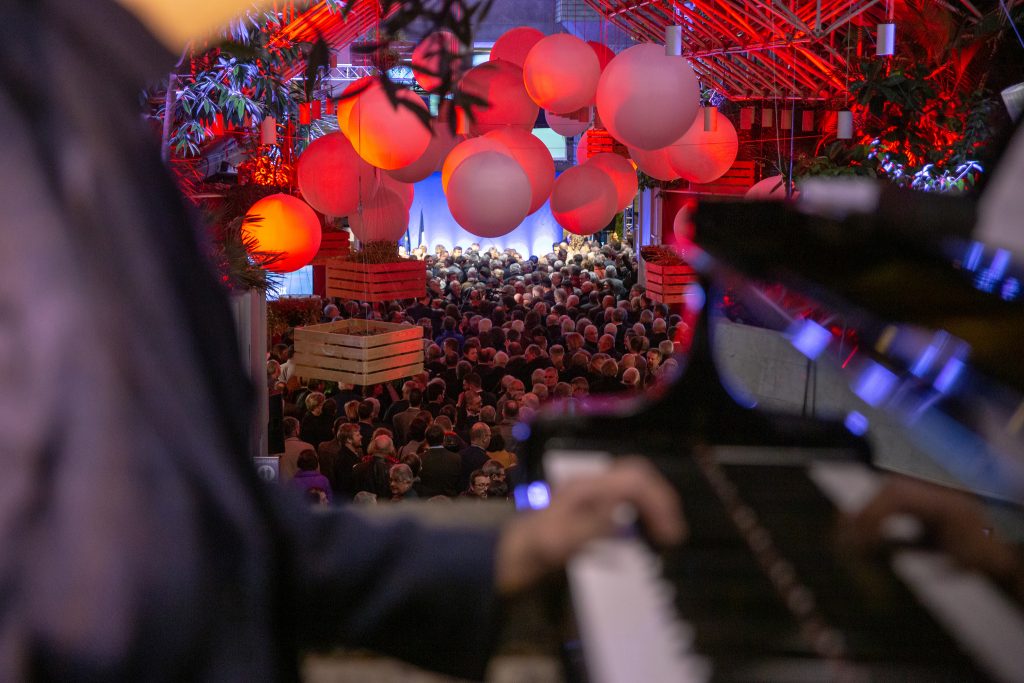 plafond de ballons suspendus avec un pianiste en premier plan et la foule en second