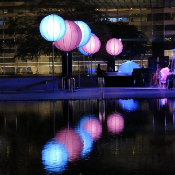 Ballons lumineux logotypés de différentes, devant bassin d'eau